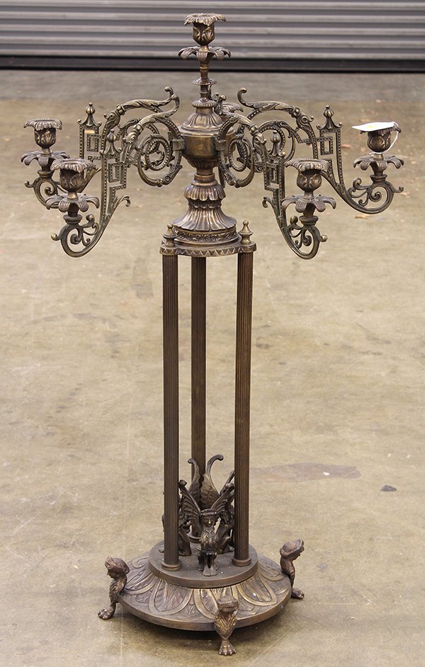 Renaissance style large patinated metal six light cande: Renaissance style large patinated metal six light candelabra with acanthus scroll branches and floral receivers supported by three fluted pillars surrounding humanistic griffins, and raised on a circu
