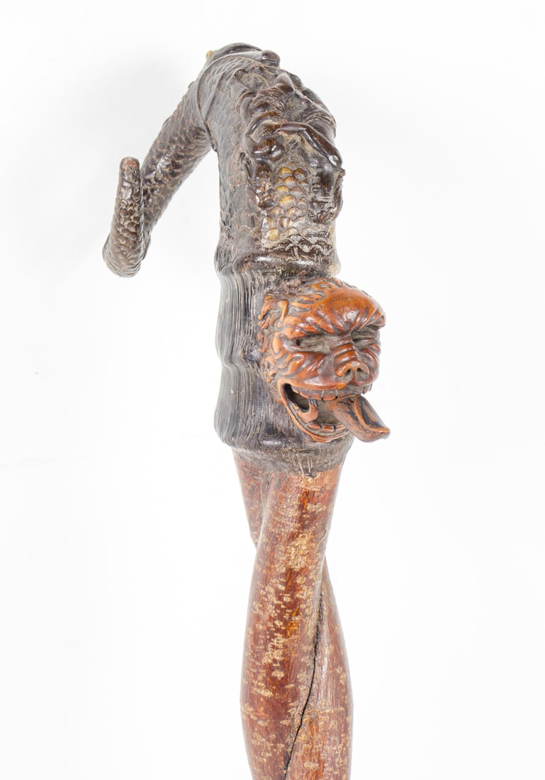 A German horn and wood witch walking cane: A German horn and wood witch walking cane, circa 1840, engraved with mythological beast, nude figures and grotesque face with phallic tongue, on double twisted branch shaft and brass ferrule, 35.5"h. 