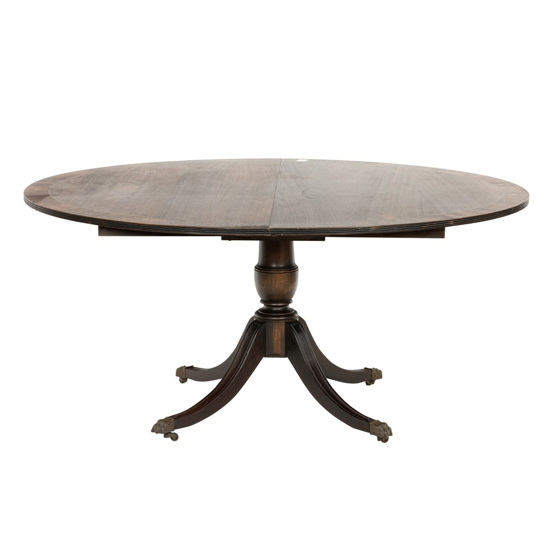 A Regency style mahogany dining table: A Regency style mahogany dining table, the banded top with two 24" leaves above the pedestal base rising on outswept legs terminating on brass capped casters, 27"h x 100"l (extended) x 54"d