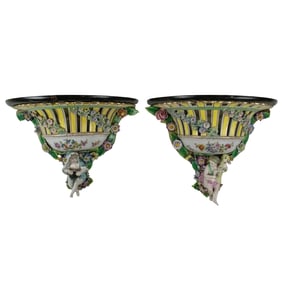 A Pair of German Dresden porcelain putti wall brackets of floral and foliate embellished urn form