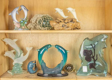 A collection of six figures of dolphins in bronze, ceramic and acrylic with two floats