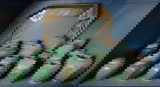 A collection of twenty one Chinese green glazed pots, with a tole tray