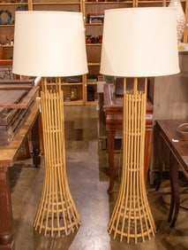 A pair of rattan style floor lamps with shades