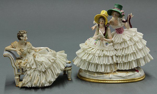 German porcelain crinoline figures: (lot of 2) German porcelain crinoline figures, including a beauty reclining on a chaise lounge, together with a figural group of two beauties wearing bonnets. The second rests on a round base with gil