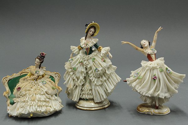 German porcelain crinoline figures: (lot of 3) German porcelain crinoline figures, including a dancer on an oval base 7"h. 4.5"w., a beauty seated on a green settee 5.5"h. x 4.5"w., and a beauty wearing a bonnet standing on a round base