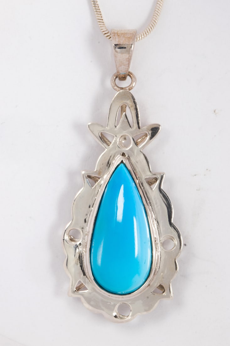 A Turquoise and silver necklace: A Turquoise and silver necklace centering a pear-shaped turquoise measuring approximately 24.15 x 11.34 x 5.80 mm, suspending from snake link chain; 12.70 grams; pendant length: 2 in
