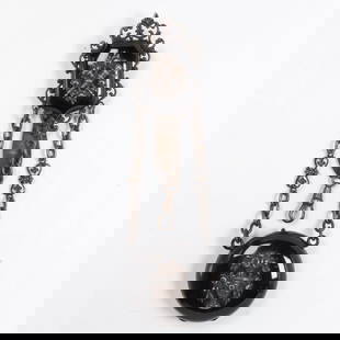 A Victorian pocketwatch chatelain: A Victorian pocketwatch chatelainfeaturing two cast aspects depicting torches and amphora, within black painted metal casing; 51.00 grams; length: 5 1/2 in