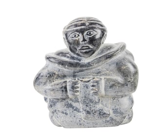 An Inuit soapstone figure of a seated woman softening a boot