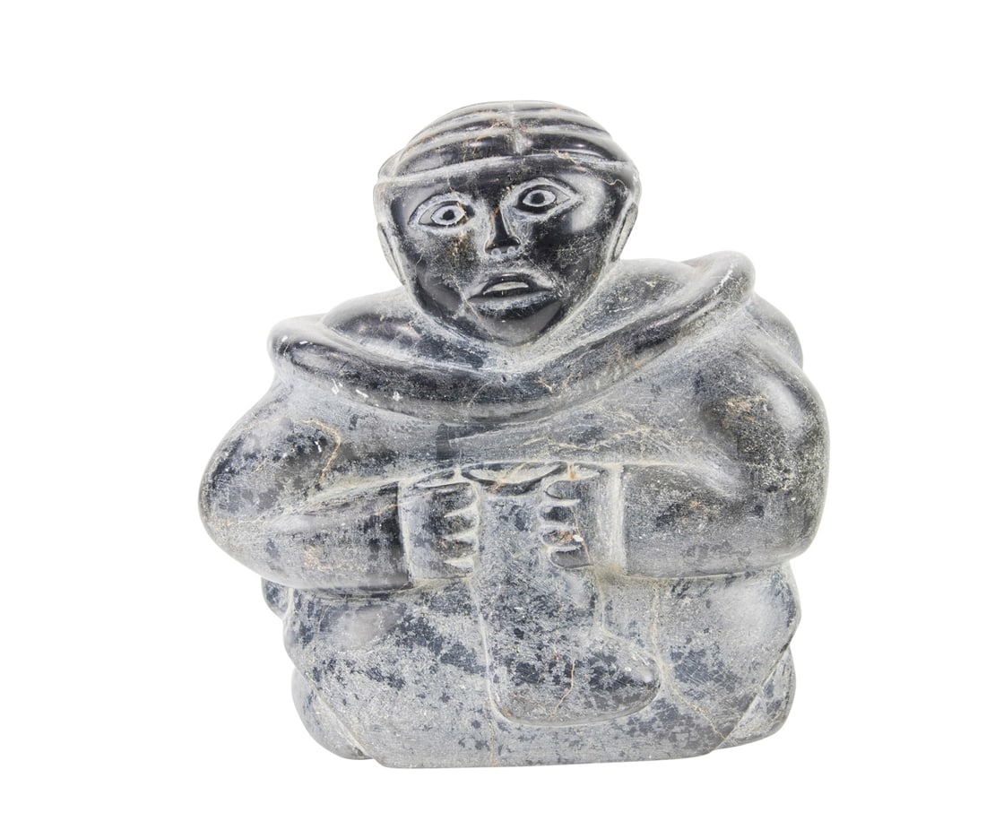 An Inuit soapstone figure of a seated woman softening a boot: An Inuit soapstone figure of a seated woman softening a boot, unsigned, 8.5"h