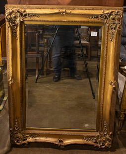 A large Rococo style gilt framed beveled mirror: A large Rococo style gilt framed beveled mirror, 47"h x 35"w