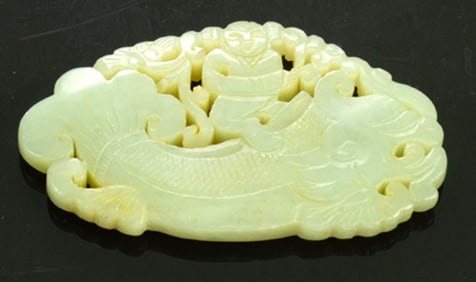 A Chinese celadon jade boy and dragon fish pendant