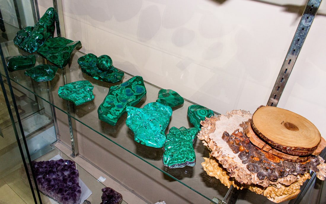 A group of twelve polished malachite specimens with five wooden slabs: A group of twelve polished malachite specimens and five wooden slabs, greatest stone approximately 5.5" h x 8" w x 6" d, includes maple burl specimen bowl signed and dated 'Fred Wilson 2005', 10"dia.