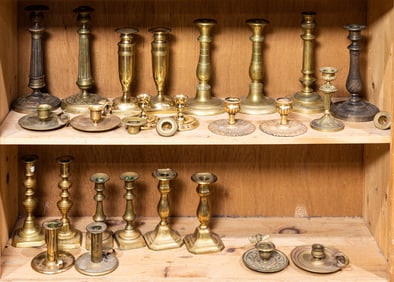 Two shelves of mainly brass candlesticks and chambersticks