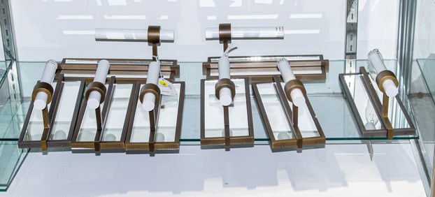 A group of eight contemporary patinated metal wall sconces with mirror backs