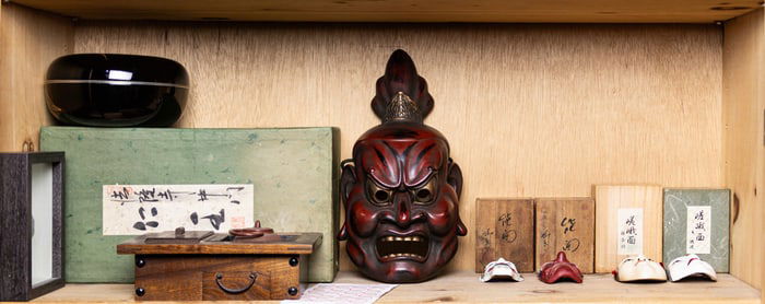 A shelf of Japanese Noh masks and other decorative items