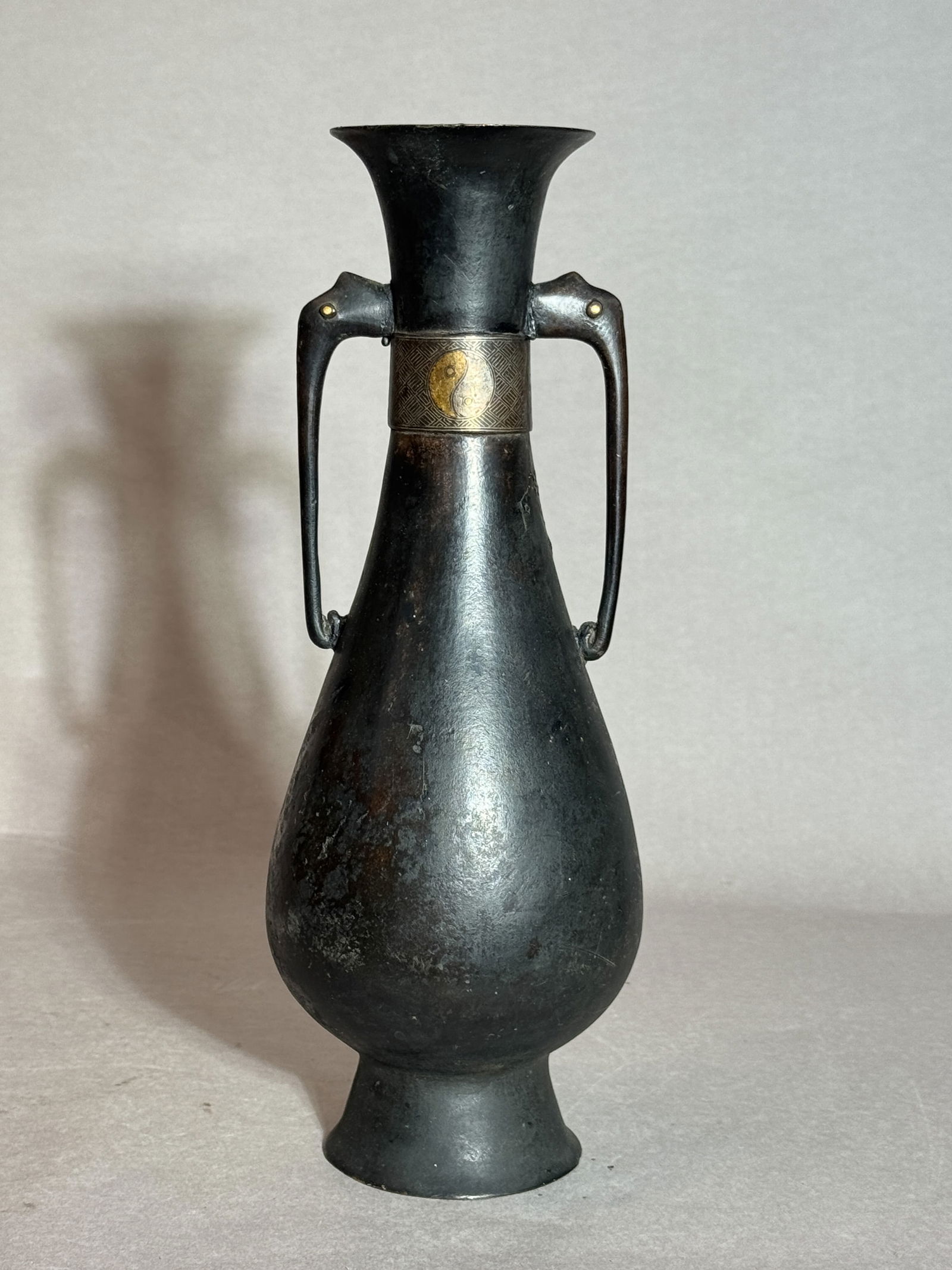 Japanese Bronze Vase with Gold and Silver: Japanese antique bronze vase with gold and silver inlay of ying and yang, double elephant ear with gold inlaid eye. 11.75"h (29.85 cm) Condition: area of death and crack NOTE: THIS ITEM IS IN NEW YORK