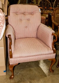 A vintage pink upholstered armchair with button tufted back and raised on cabriole legs