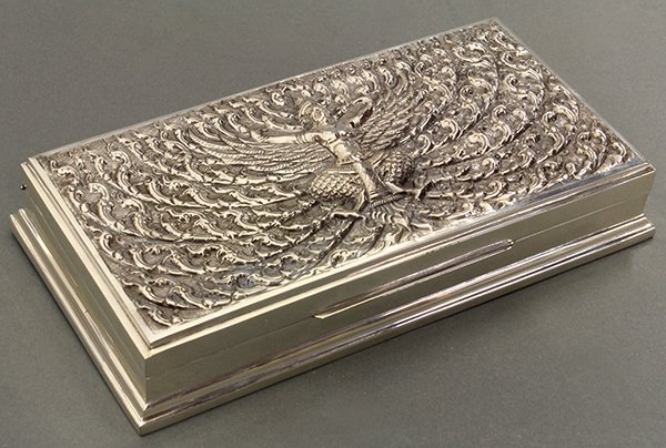 Siam sterling silver mounted box.: Siam sterling silver mounted wood box, the hinged cover having a finely hammered ground centered with Garuda surrounded by floral scrolls, and opening to divided compartments, 1.5"h x 8.25"w x 4.25"d