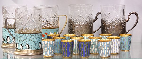 Russian associated enamel barware, circa 1950: (lot of 19) Russian associated barware, circa 1950, consisting of two champleve decorated silver plate stands depicting penguins at play; champleve on brass stand with floral decoration; pair of silve