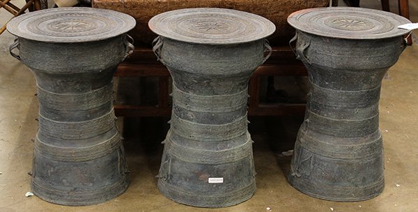 Pair of Southeast Asian bronze rain drums: (lot of 3) Southeast Asian bronze rain drums, each having separately cast tops with a starburst medallion encircled with concentric bands bounding geometric patterns, the shaped body cast with raised 