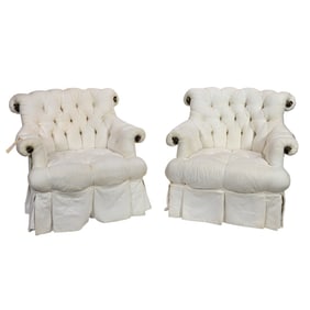 A pair of white tufted armchairs