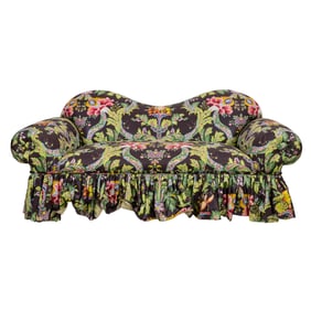 A sofa upholstered in in green, pink and blue floral pattern on brown ground