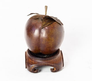 A bronze model of an apple on wood stand