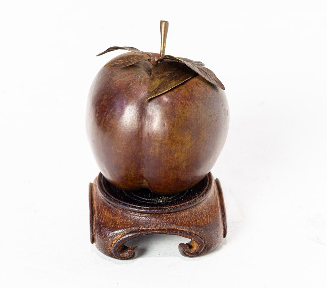 A bronze model of an apple on wood stand: A bronze model of an apple on wood stand, unmarked, 3"dia. Provenance: The Carole Harris Collection, River Ranch. The interiors guided by Parish-Hadley (Sister Parish) reflect the distinguished collec