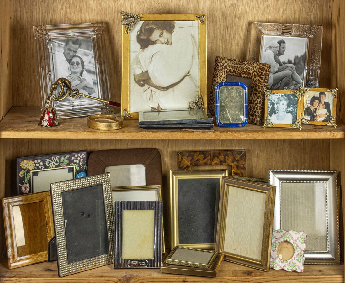 A group of frames including examples by Rosenthal, Linda Levinson, hardstone and faux-leopard: Two shelves of frames including examples by Rosenthal, Linda Levinson, hardstone and faux-leopard, with a Two's Company's enameled candlesnuffer, greatest 11"h x 9"w. Provenance: The Carole Harris Col
