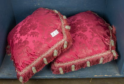 A pair of burgundy red damask pillows with fringe