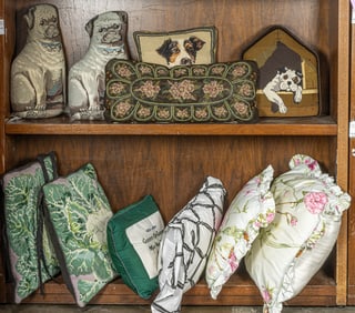A group of pillows depicting dogs, including needlepoint and beaded