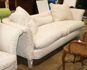 A custom contoured sofa, with down cushions and pillows, raised on silver tapered legs