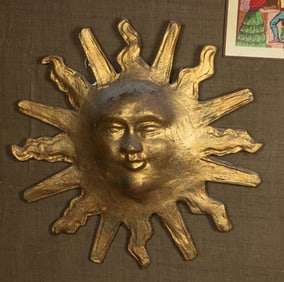 A gilt papier mache sun face wall sculpture and leaded glass window