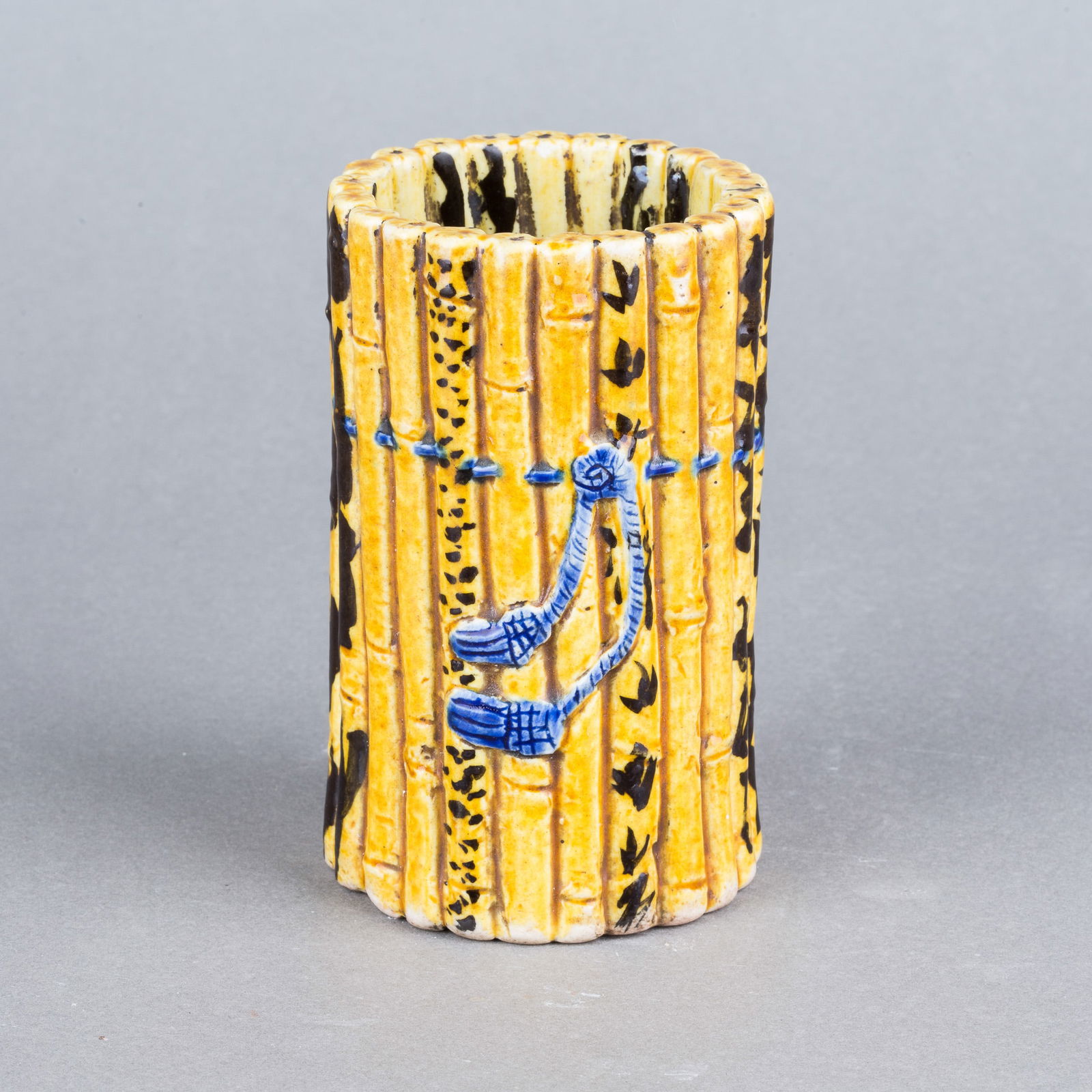 A Porcelain 'Bamboo' Brush Pot: A porcelain 'bamboo' brush pot. In a form of bamboo style, covered with yellow glaze and painted with bamboo leaves. 4.33"h x 2.56"d (11 x 6.5 cm) NOTE: THIS ITEM IS IN LOS ANGELES.