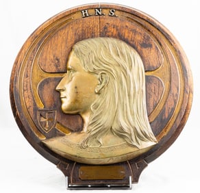 An Art Nouveau brass high relief profile of a youth on wood plaque