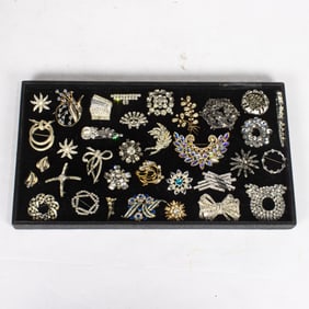 Twenty-nine rhinestone costume jewelry brooches with two pairs of earrings and a bracelet
