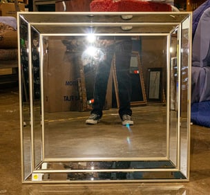 A contemporary square wall mirror with beveled glass frame