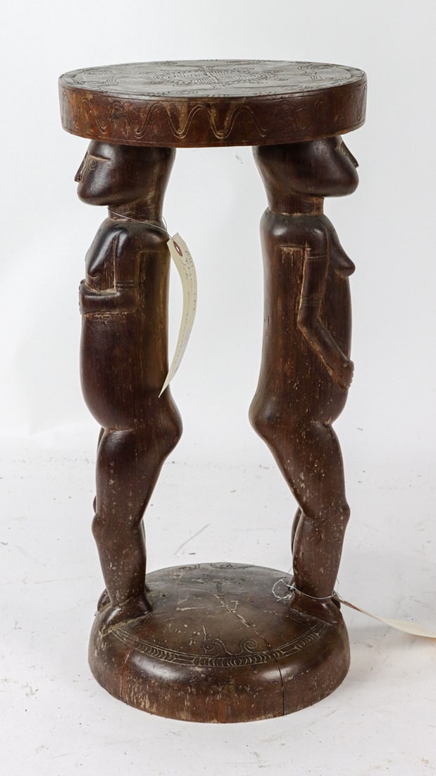 An Oceanic carved stool: An Oceanic carved stool, likely Papua New Guinea, the round seat supported by two figures, 20.5"h x 10"dia