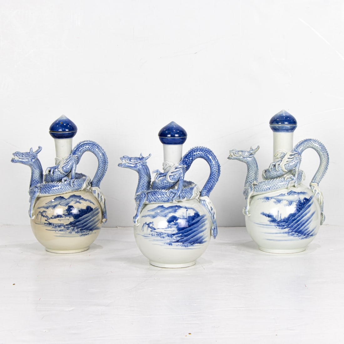 Three Hirado blue and white 'dragon' ewers: Three Hirado blue and white 'dragon' ewers. Meiji period. from 10.125" to 10.75" high.