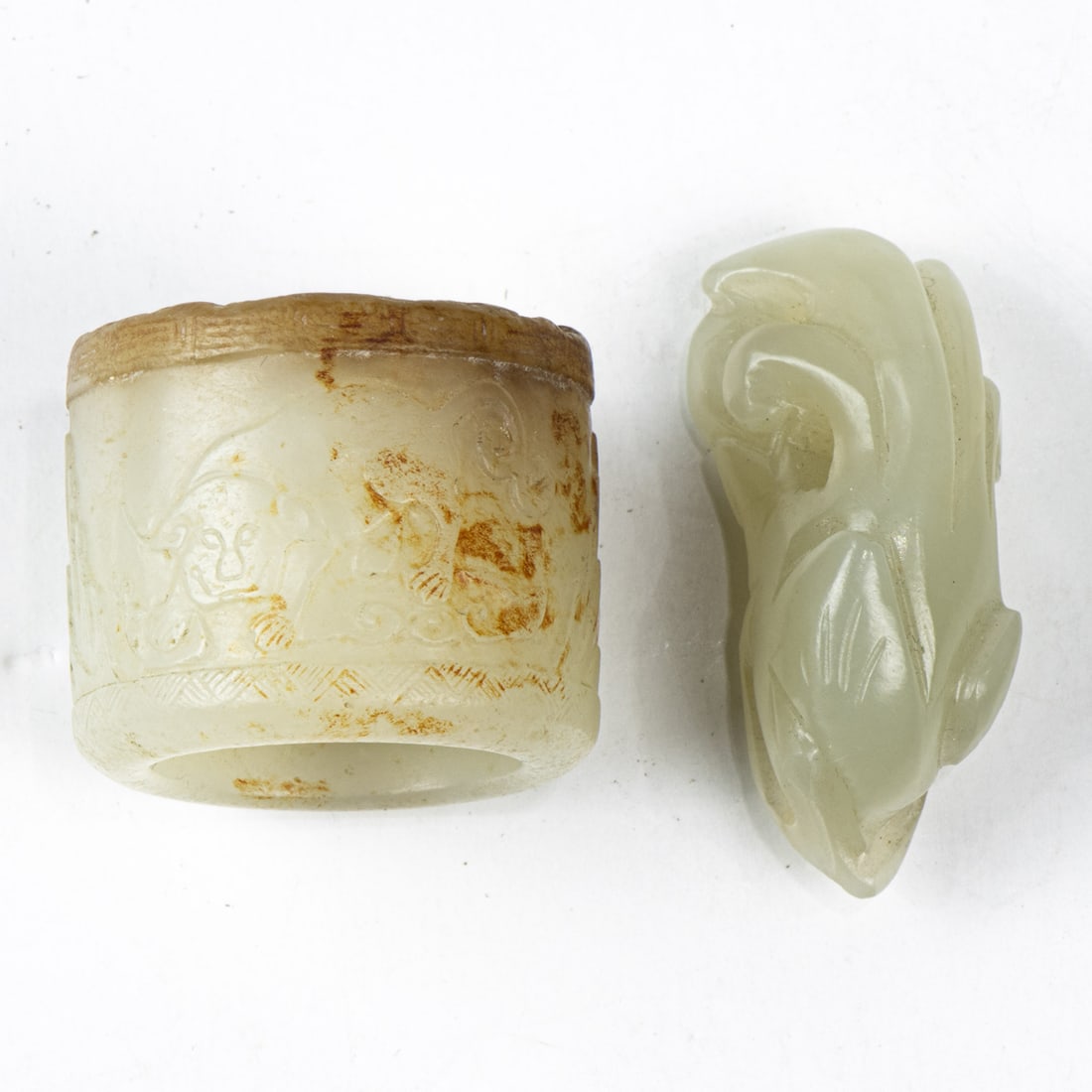 Two Chinese white jade carvings: Two Chinese white jade carvings. Comprising an archer's ring and a toggle, Qing dynasty, 1.125" and 1.5" wide.