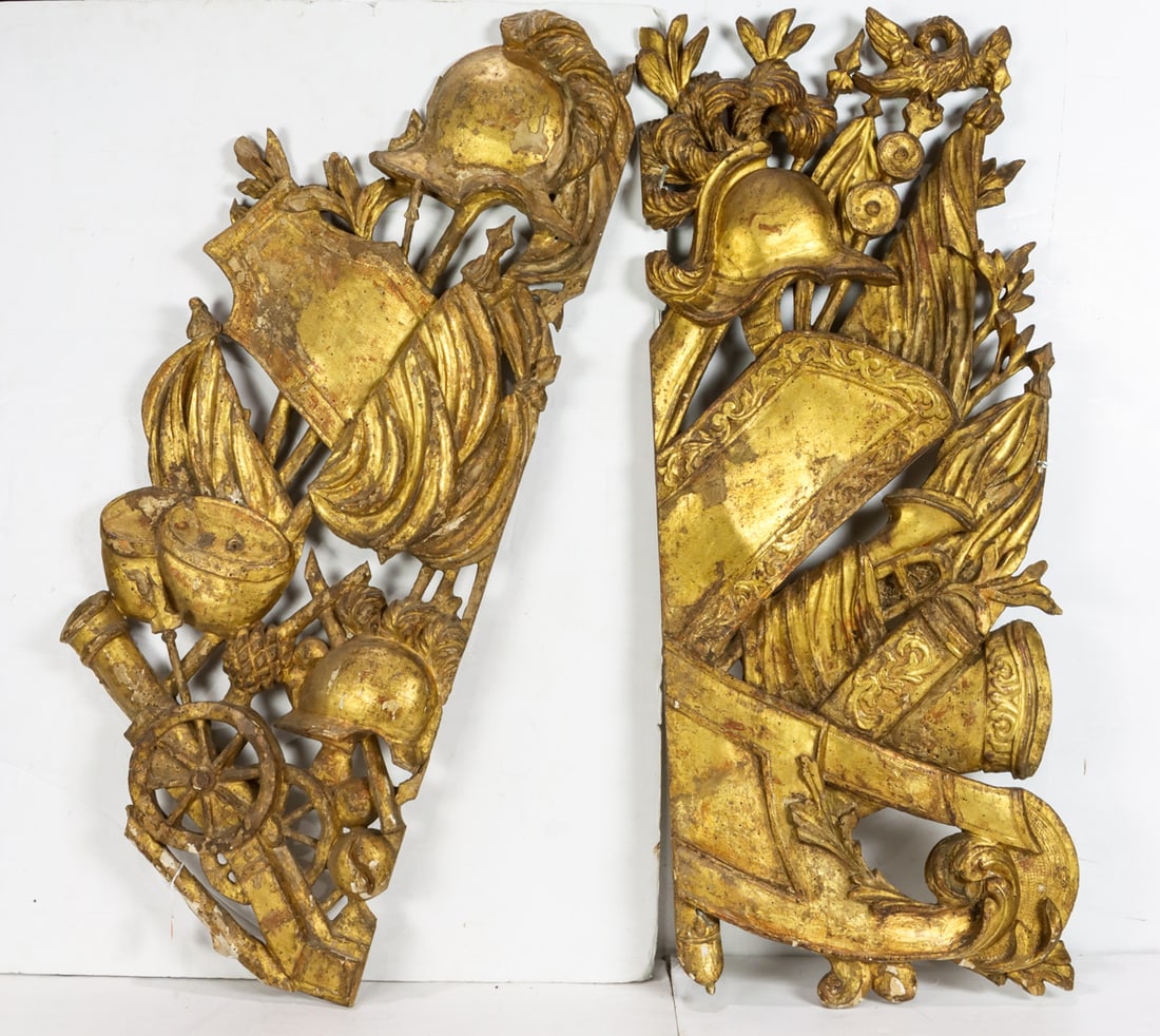 A near pair of Neoclassical giltwood appliques in the form of military trophies: A near pair of Neoclassical giltwood appliques in the form of military trophies, late 18th/early 19th century, featuring various military motifs including shields and weaponry, 39"h x 16"w and 40"h x