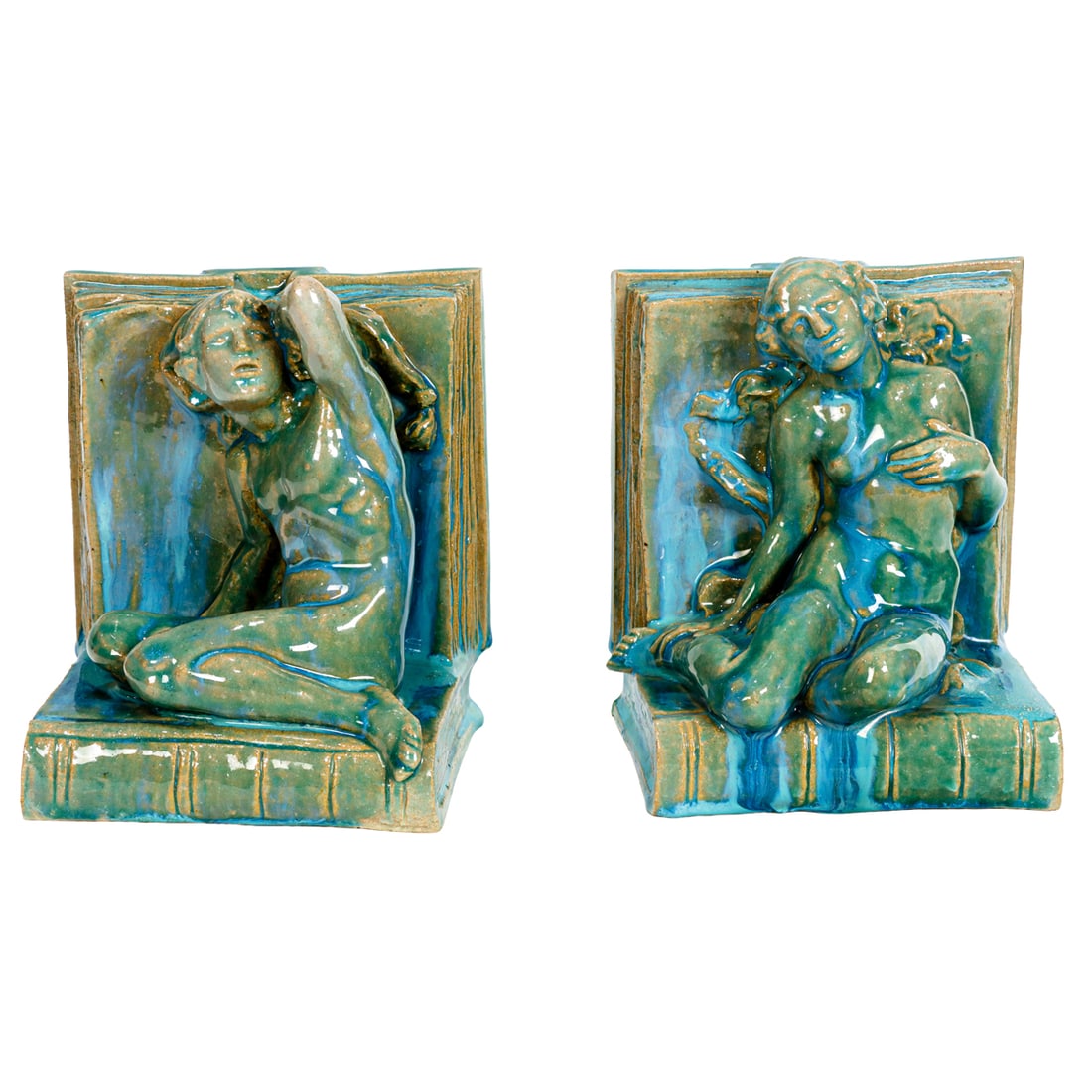 A pair of Arts & Crafts style turquoise flambe glazed pottery bookends: A pair of Arts & Crafts style turquoise flambe glazed pottery bookends, each modeled as a Classical male or female nude seated on an open book, unmarked, 6.5"h x 5.5"w x 4.75"d