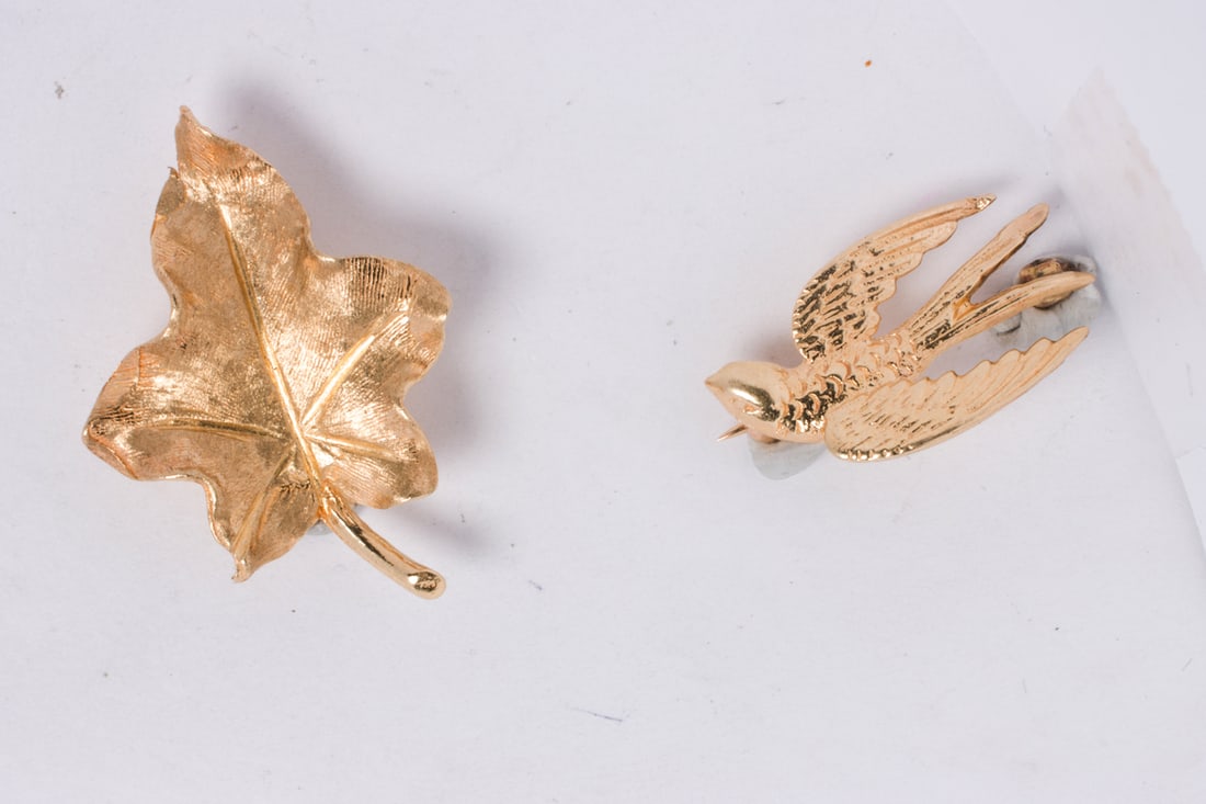 Two 14k gold pins: Two 14k gold pinsOne designed as a swallow, one designed as a leaf; 4.85 grams