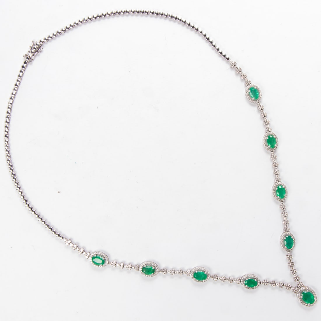 An emerald, diamond and 18k white gold necklace and earrings: An emerald, diamond and 18k white gold necklace and earringseach of similar design featuring 13 oval-cut emeralds, each framed by round brilliant-cut diamonds weighing approximately 2.50 carats;