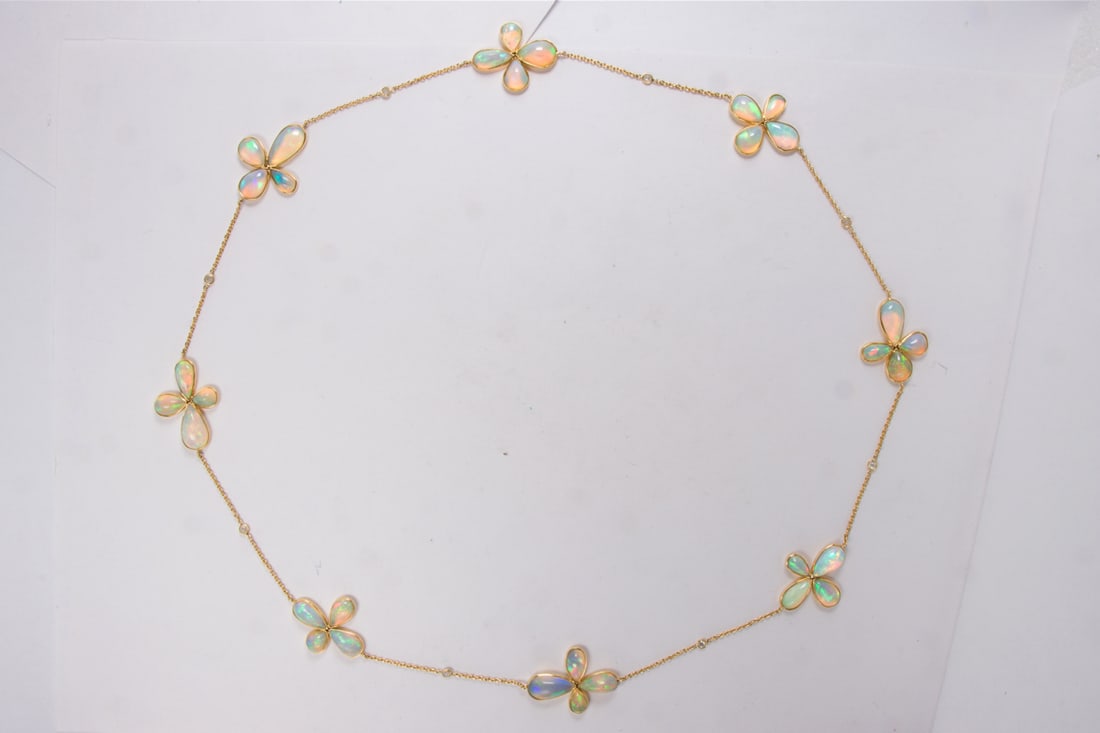 An opal, diamond, and 18k gold necklace: An opal, diamond, and 18k gold necklaceDesigned with 32 pear-shaped, bezel-set opal cabochons of varying sizes arranged as clovers, interspersed by round-cut diamonds; length: 25 in; 19.30 grams