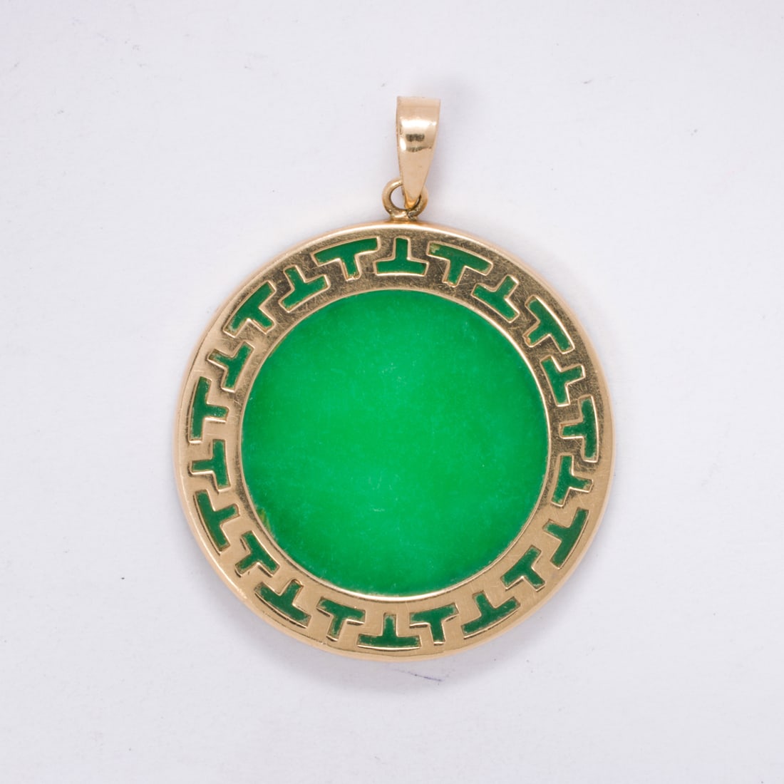 A jade and 14k gold pendant: A jade and 14k gold pendantDesigned as a round-shaped jade disc measuring 26.07 mm across, set within 14k gold bezel; length: 1 1/4 in; 4.70 grams