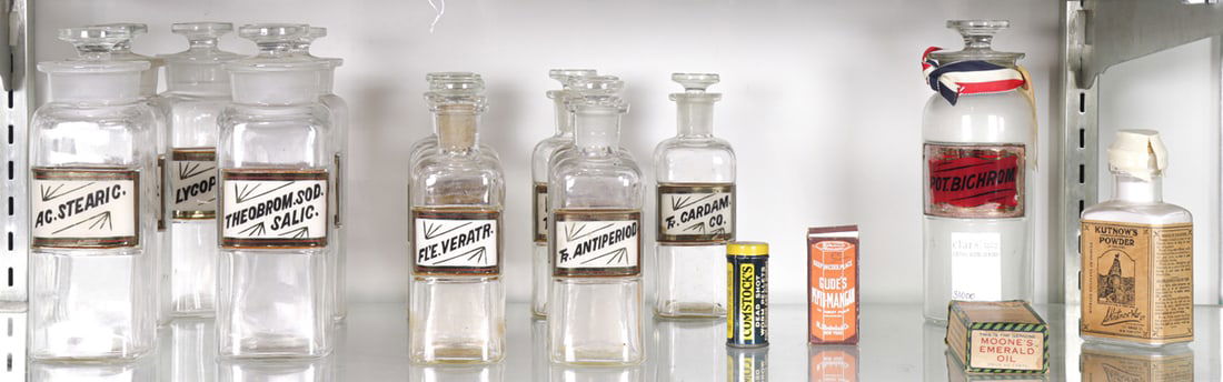 A collection of clear glass apothecary bottles and medicines: A collection of clear glass apothecary bottles and medicines, comprising (6) clear bottles with labels and stoppers, 7.75"h; (9) clear bottles with labels and stoppers, 6.75"h; (1) clear glass bottle