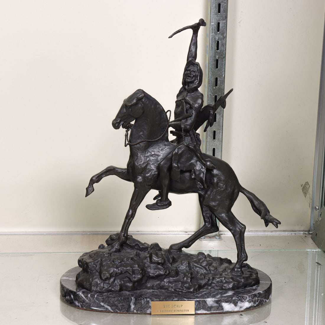 A Contemporary patinated bronze figure of a Native American on horseback: A Contemporary patinated bronze figure of a Native American on horseback, after a model by Frederick Remington, raised on marble plinth, 13"h x 10"w