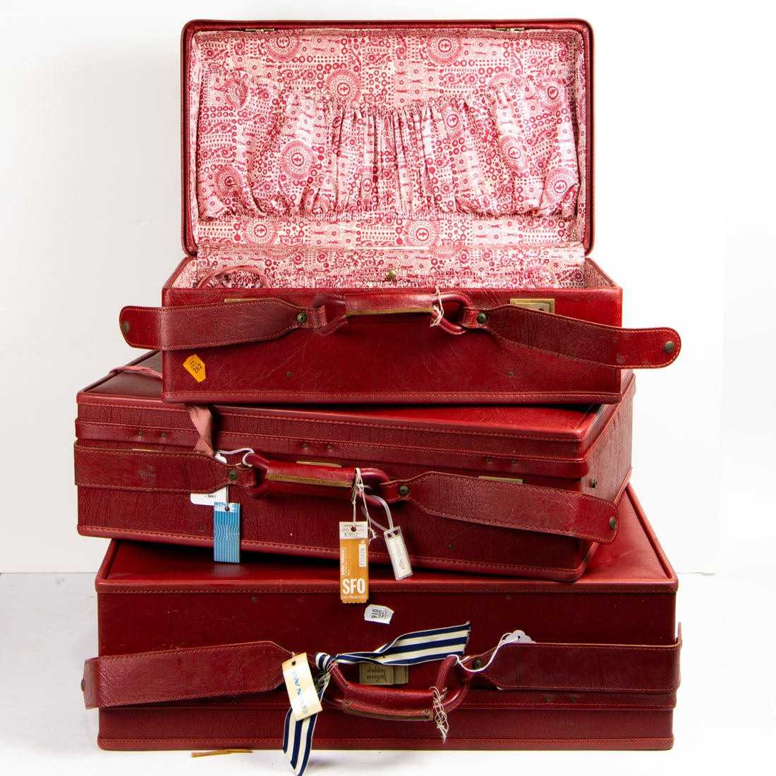 A suite of three Hartman red leather hardside suitcases: A suite of three Hartman red leather hardside suitcases, each with printed fabric interior, greatest 19.5" x 26 x 8" (excluding handles). Provenance: The Collection of Adolphus Andrews Jr. and Emily T