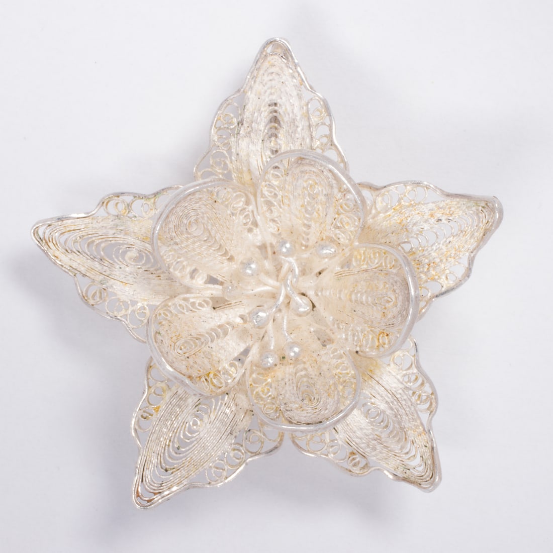 A silver filigree flower pendant: A silver filigree flower pendantFeaturing ornate filigree, designed as a flower; length: 1 3/8 in; 4.55 grams